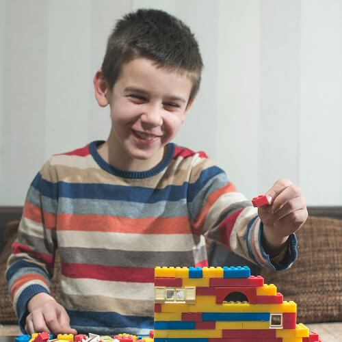 Menino construindo com blocos coloridos